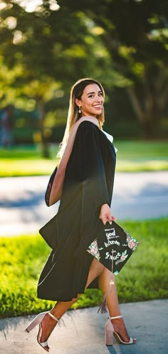 a woman in a black dress is walking down the street with her hand on her hip