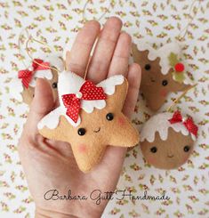 a hand holding three christmas ornaments in the shape of gingerbreads with red bows