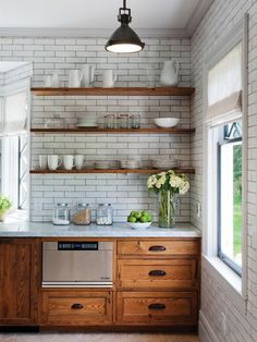 a kitchen with white brick walls and open shelving on the wall, along with wooden cabinets