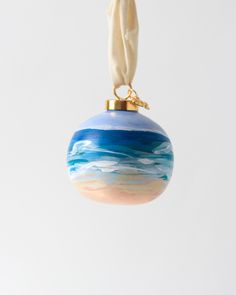 a glass ornament hanging from a string on a white background with blue and pink designs