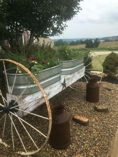 an old wagon is sitting in the gravel with two planters on it's side