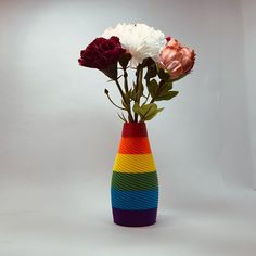 there is a vase with flowers in it on the table and one has a rainbow stripe