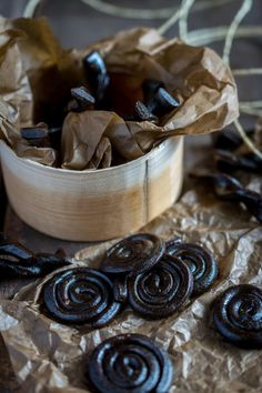 there are chocolate candies in a bowl on the table next to some brown paper