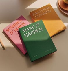 three books sitting on top of a table next to a cup and pencils in front of them