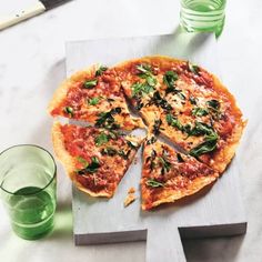 a pizza sitting on top of a cutting board next to two glasses and a knife