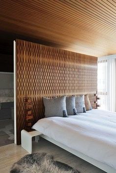 a large bed sitting in the middle of a bedroom next to a wall with wooden slats on it