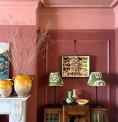 a living room with pink walls and two vases on top of the fireplace mantel