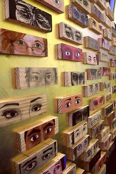 a woman standing in front of a wall covered with wooden boxes and eyeballs on them