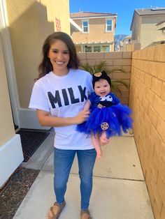 a woman holding a baby wearing a shirt that says milk