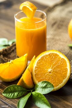 a glass of orange juice next to sliced oranges on a wooden table with text that reads healthy skin tip 1 feed your face cut a strawberry, and apply