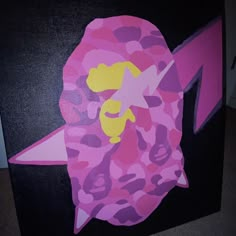 a pink and purple camouflage print hat on a black box with the letter m painted on it