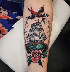 a woman's arm with a ship and flowers on it