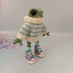 a knitted frog wearing blue sneakers and a sweater