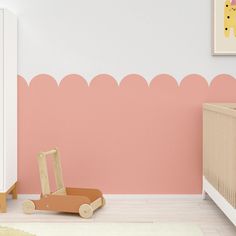 a baby's room with pink and white walls, wooden furniture and a giraffe wall decal