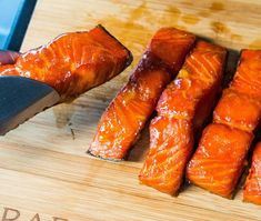 someone is slicing salmon on a wooden cutting board