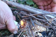 someone is lighting a lighter in the ground with sticks and wood shavings on it