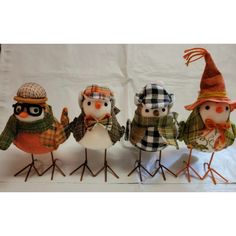 four small birds wearing hats and scarves are standing in a row on top of each other