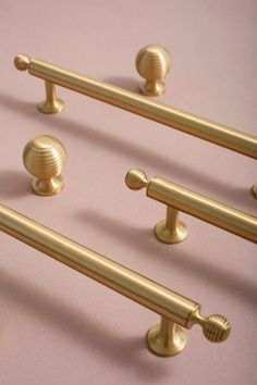 four golden handles and knobs on a pink surface