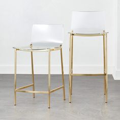 two white and gold bar stools sitting side by side