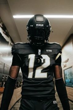 a football player in uniform walking down the hall with his hand on his hip and wearing a helmet