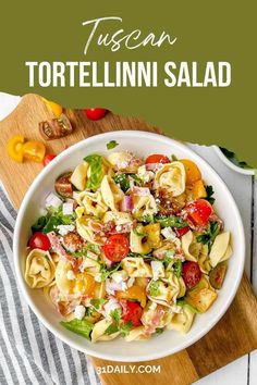 a white bowl filled with tortellini salad on top of a wooden cutting board