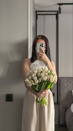 a woman taking a selfie while holding a bouquet of flowers