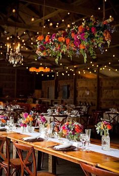 the tables are set up for an event with flowers hanging from the chandelier