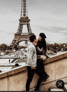 a man and woman standing next to each other near the eiffel tower in paris