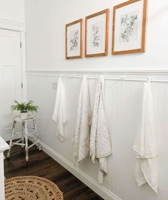 three framed pictures hang on the wall next to white towels and a plant in a pot