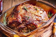 a roasting pan filled with meat and vegetables on top of a wooden cutting board