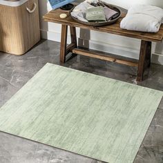 a bathroom area with a wooden bench, towel rack and toilet paper on the floor