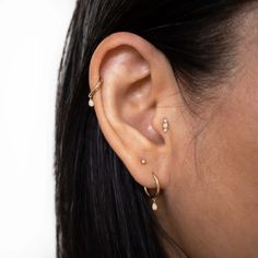 a close up of a woman's ear with three piercings on her left side