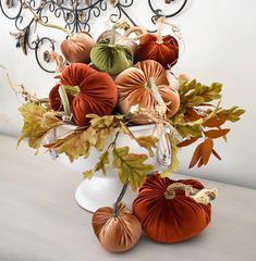 a vase filled with pumpkins and leaves on top of a table next to a clock