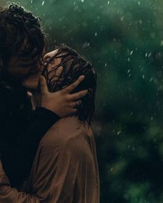 two people embracing each other in the rain