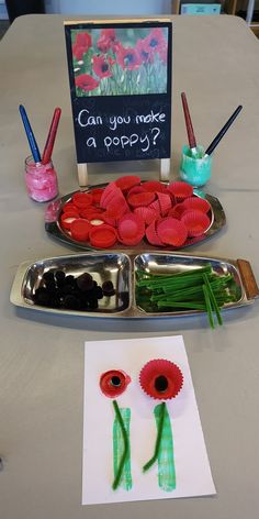 two trays with paper flowers on them and a sign that says can you make a poppy?