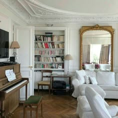 a living room filled with furniture and a piano in front of a large book shelf