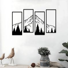 three black and white paintings on the wall above a table with a potted plant