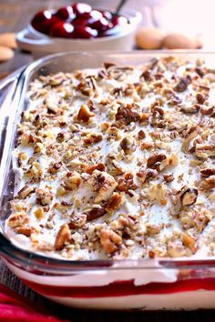 a casserole dish with nuts and cream in it on a table next to cherries