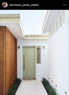 a white house with a green door and some plants