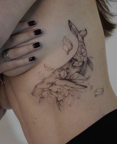 a woman's stomach with a fish and flowers tattoo on her side ribcage