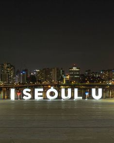 an illuminated sign that reads i seouluu in front of a cityscape