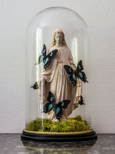 the statue is under a glass dome with butterflies on it