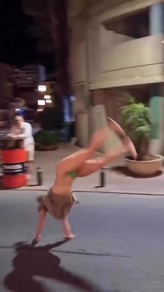 a woman is dancing on the street at night