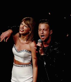 a man and woman standing next to each other in front of a microphone on stage