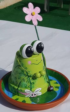 a cake shaped like a frog with large eyes and a flower sticking out of its mouth