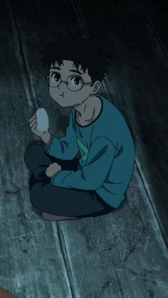 a boy sitting on the floor holding an object in his hand