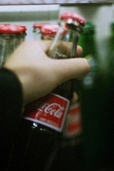 a person is holding several soda bottles in their hand