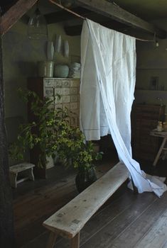 a wooden bench sitting under a canopy in a living room next to a table and potted plant