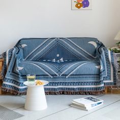 a living room with a couch covered in a blue blanket next to a coffee table