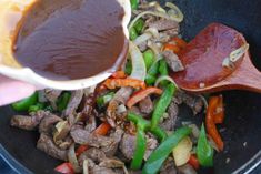 someone is adding sauce to the stir fry food in a pan with vegetables and meat